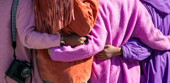 A group of people in purple jackets with their arms around each other
