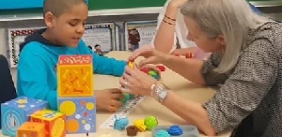 一个妈妈在照顾者技能培训研讨会上与一个有自闭症的孩子合作。照片礼貌Mom2mom