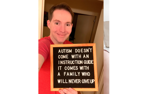 穿着红色衬衫的男人举行了一个信号标志，上面写着“自闭症没有指导指南，它带有一个永远不会放弃的家庭”